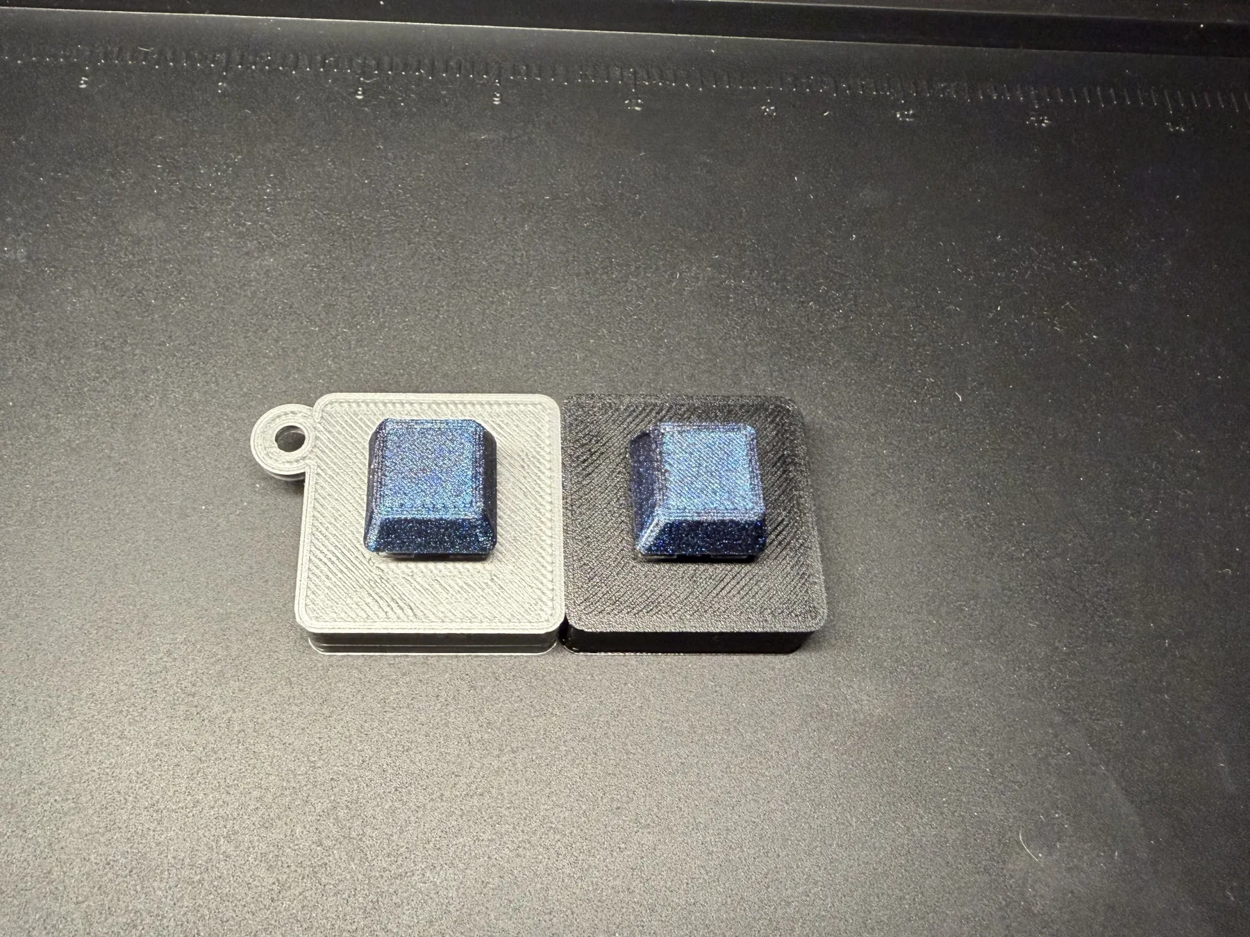 White one-key Clacky with a keychain loop beside a black one-key Clacky without a loop